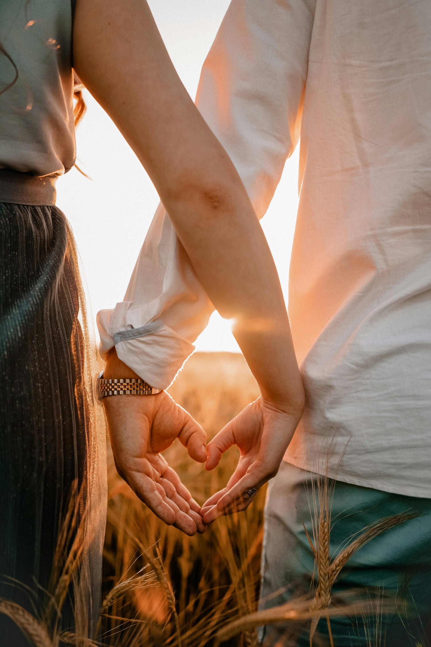 Parents making heart hands in a field